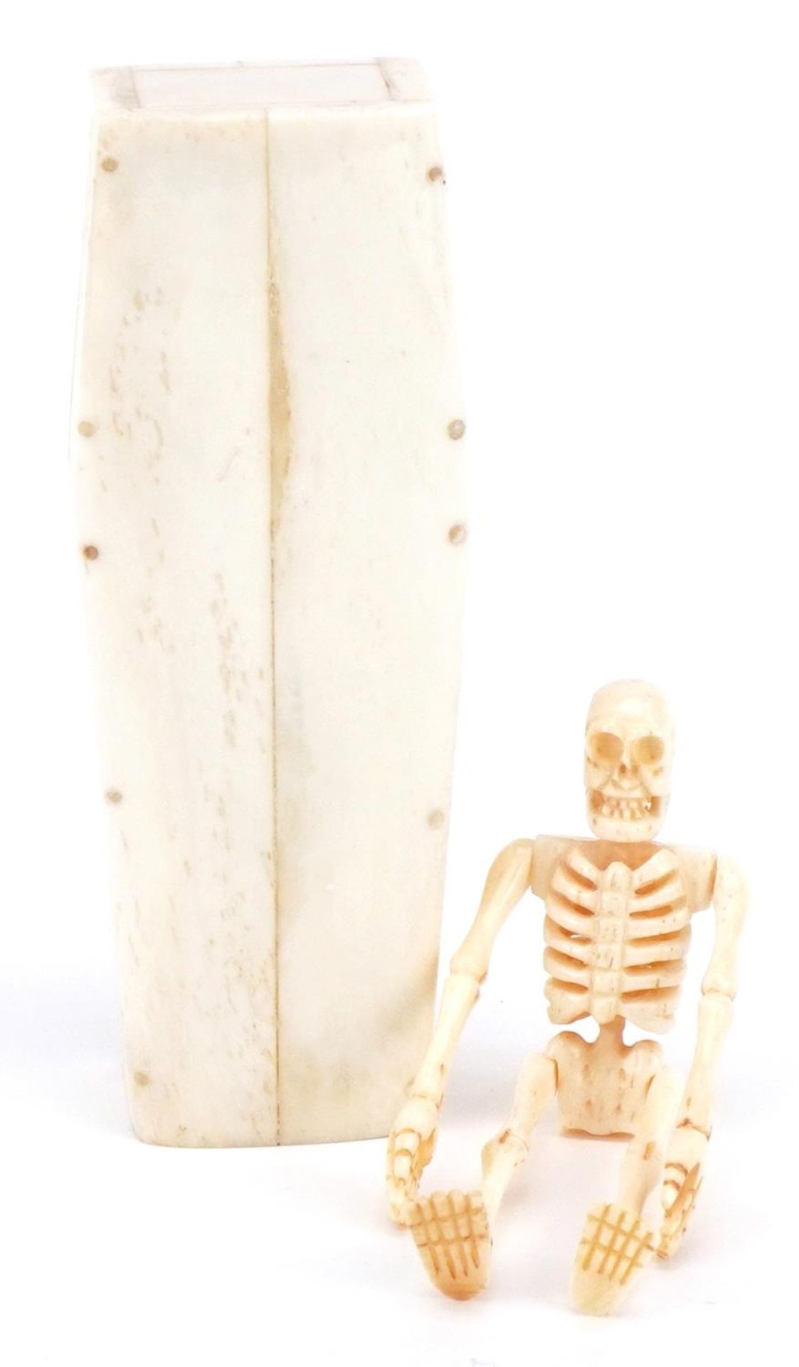 Scrimshaw style carved bone skeleton housed in a bone coffin with lift off lid, the coffin 11.5cm in