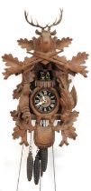 German Black Forest cuckoo clock carved with a deer's head and game having a circular dial with