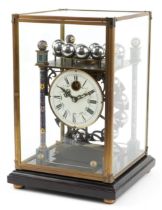 Champleve enamel rolling ball clock housed in a glazed brass case on hardwood stand, the circular