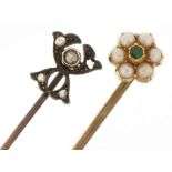 Two unmarked gold and yellow metal stickpins set with diamonds, seed pearls and an emerald, the