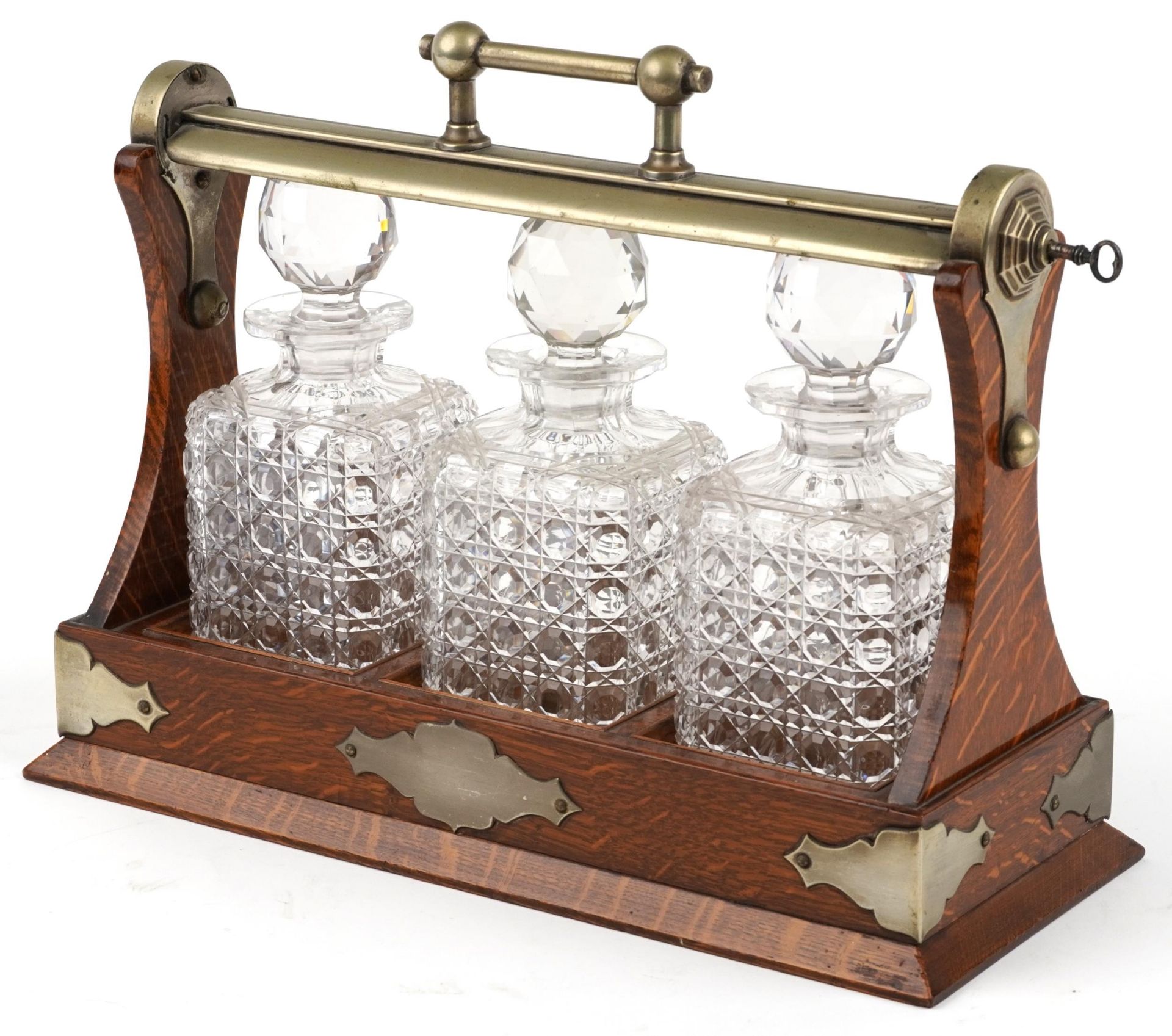 Edwardian oak Grimsell's Patent tantalus housing three cut glass decanters, 40cm wide : For