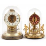 Two German brass cased anniversary clocks including one with figures and chains, the largest 24cm