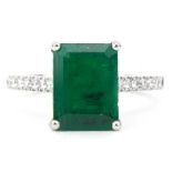Platinum octagonal step cut emerald ring with diamond set shoulders, the emerald approximately 3.0