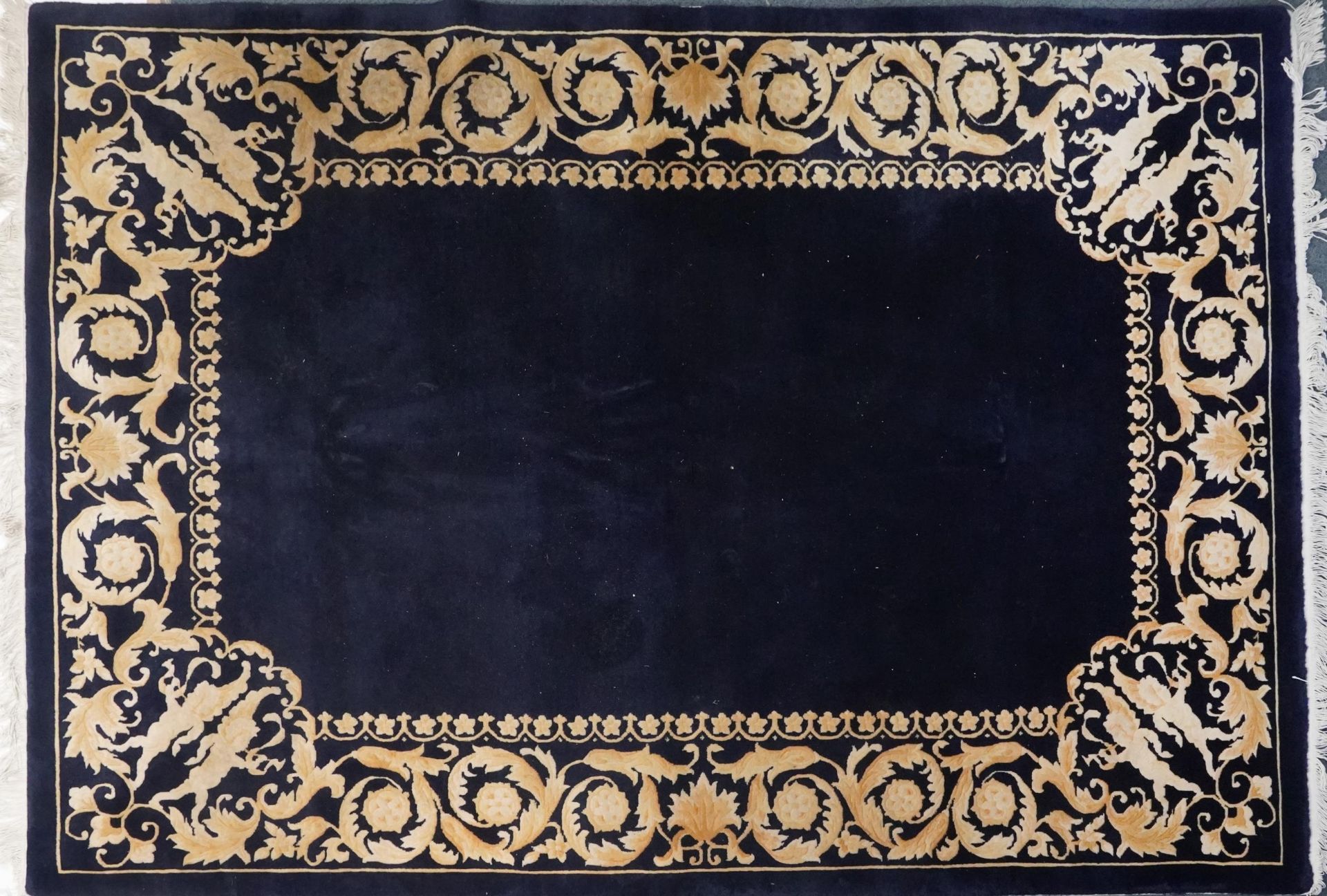 Large rectangular blue ground rug having a cream floral and Putti design border, 250cm x 169cm : For