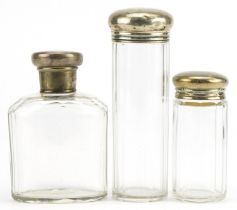 Three Victorian and later cut glass bottles with silver lids, various hallmarks, the largest 13cm