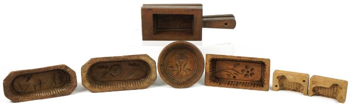 Six Antique French treen butter moulds including examples carved with flowers, the largest 20.5cm in