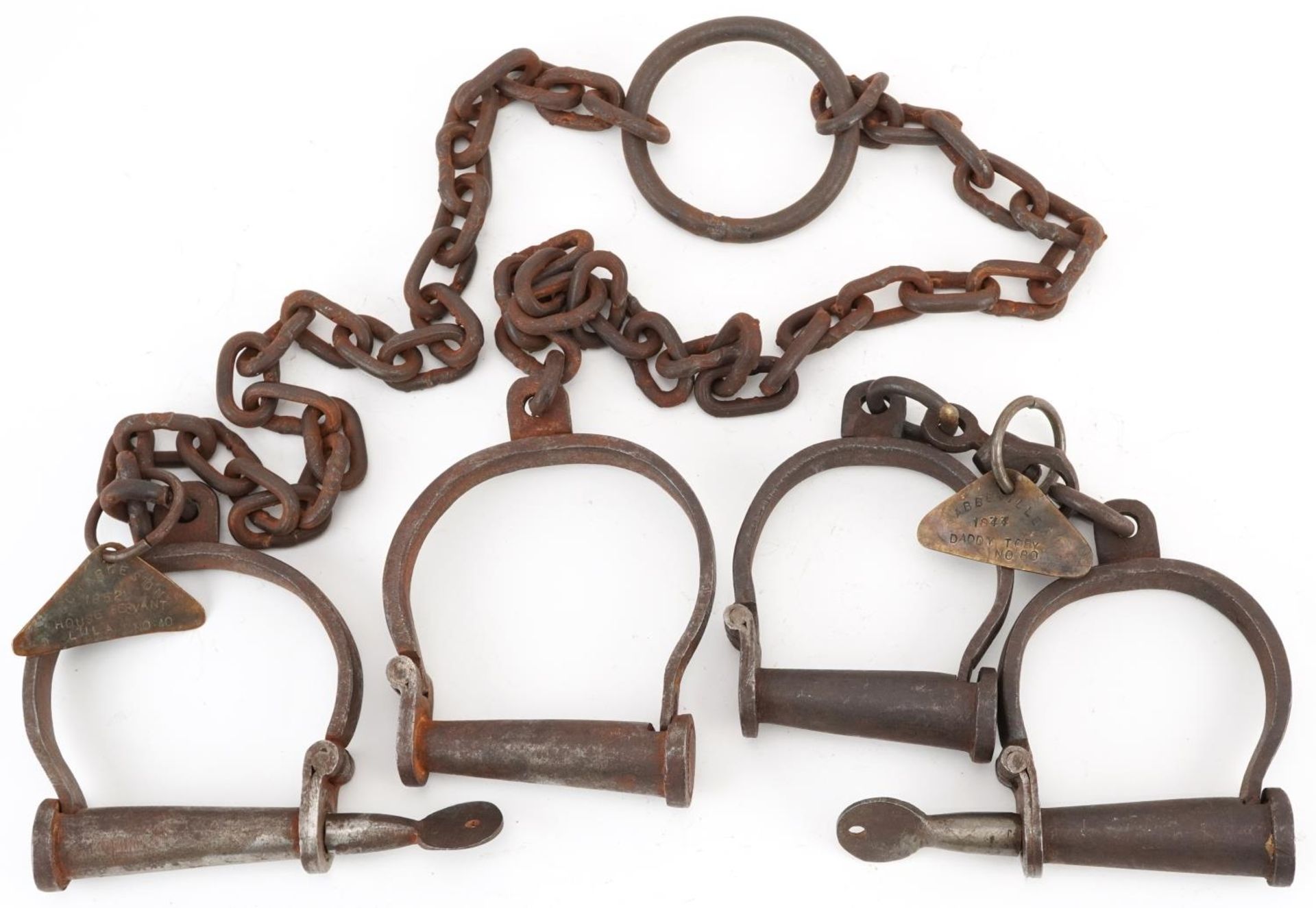 Two pairs of 19th century cast iron handcuffs with tags engraved Abbeville 1844 Daddy Toby no 88 and