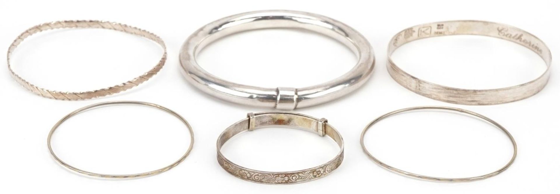 Six silver and white metal bangles including a christening bangle, the largest 8cm in diameter,