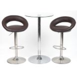 Contemporary chrome breakfast table with circular glass top and pair of adjustable stools with brown