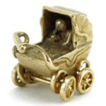 9ct gold charm in the form of a baby in a pram with rotating wheels, 1.5cm wide, 3.2g