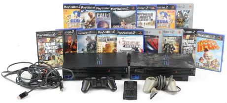 Two Sony PlayStation 2 games consoles with controllers and a collection of games