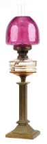 Victorian brass oil lamp with reeded column and cranberry glass shade, 73cm high