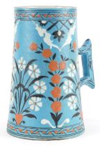 Turkish Ottoman Iznik tankard with tapering body hand painted with stylised flowers, 20.5cm high