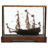 Hand painted wooden model of a rigged battleship housed in a glazed display case, 43cm H x 51cm W