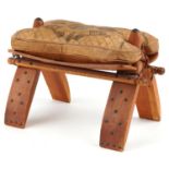 Vintage hardwood camel stool with leather upholstered cushion tooled with foliate motifs and a