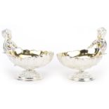 Pair of silver plated open salts in the form of Putti holding a seashell, 12cm in length