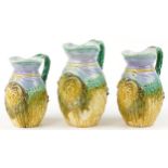 Graduated set of three Majolica jugs, each decorated in relief with a ram's head, the largest 22.5cm