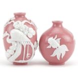 Two Chinese porcelain pink ground snuff bottles decorated in relief with fish and a crane, the