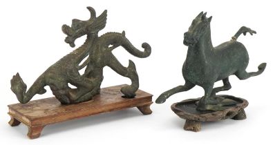 Two Chinese archaic style verdigris cast metal animals including a dragon, each raised on hardwood