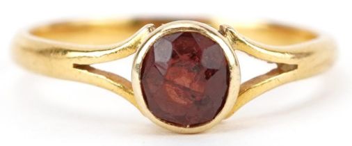 Unmarked gold garnet solitaire ring with split shoulders, tests as 18ct gold, size L, 2.4g