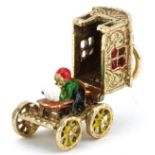 9ct gold and enamel charm in the form of a Gypsy wagon with rotating wheels opening to reveal a