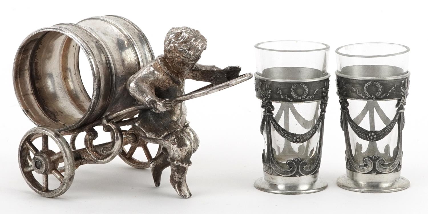 Silver plated napkin holder in the form of a boy pulling a cart and a pair of pewter and glass