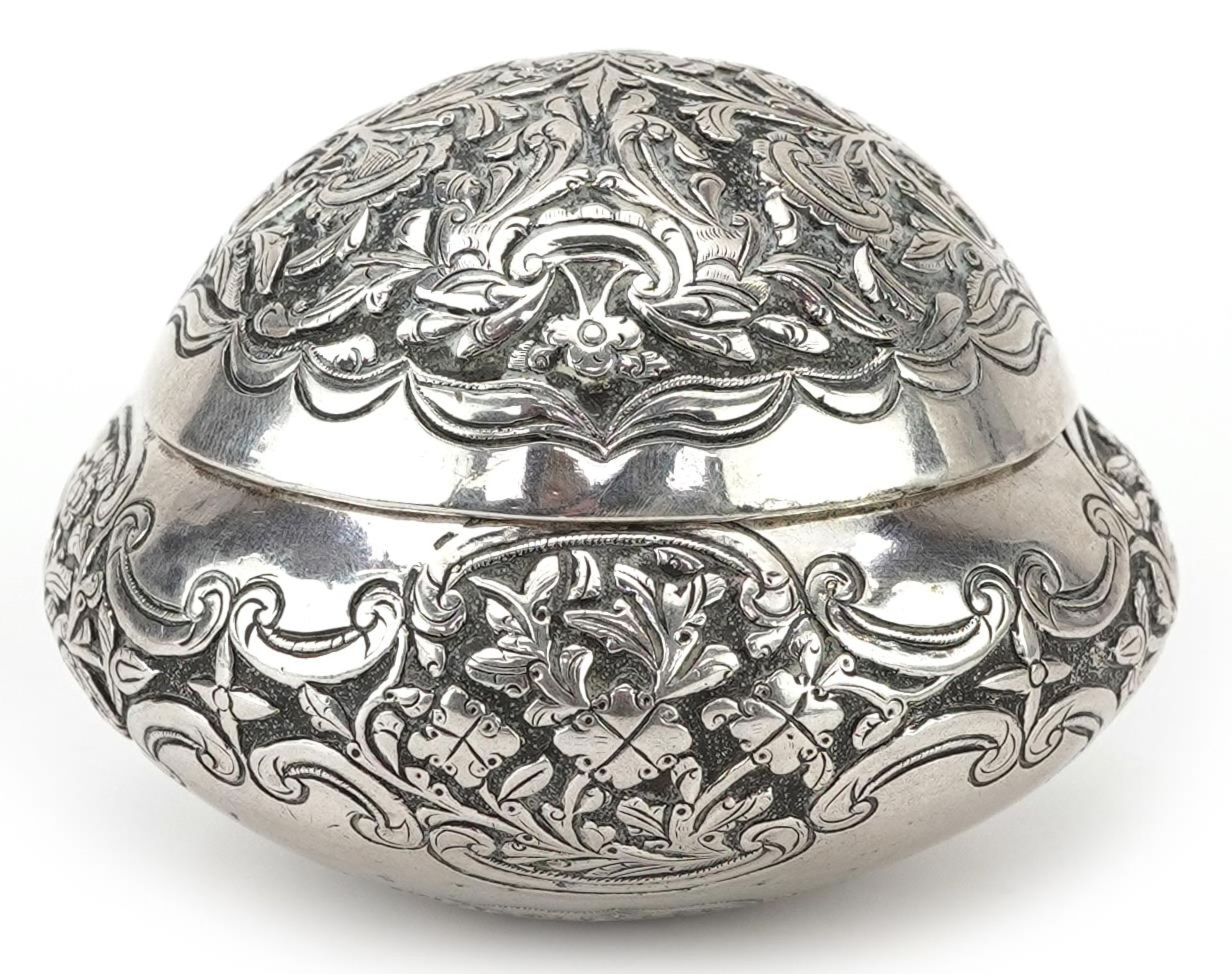 Tibetan unmarked silver bun shaped box with hinged lid profusely embossed with flowers and