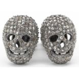 Pair of diamond set white metal cufflinks in the form of human skulls, total diamond weight