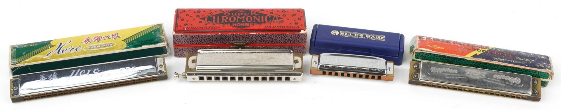 Four vintage and later harmonicas with cases comprising Hero, Blues Harp and two M Hohners