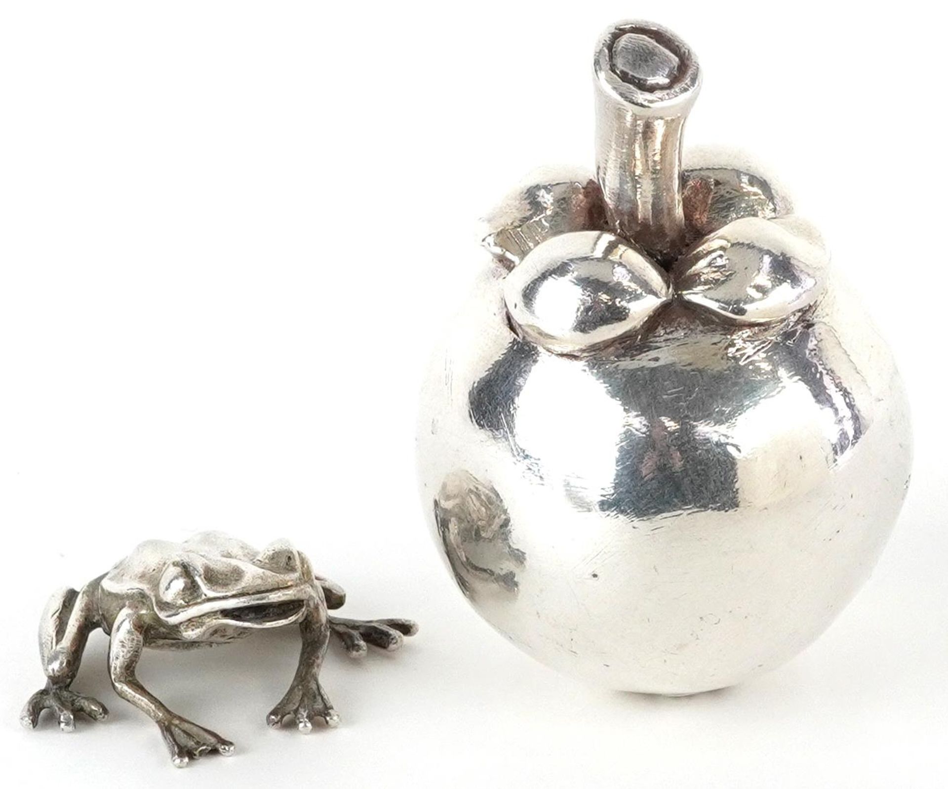 Silver model of a seated frog and a silver filled model of a pome fruit, the largest 7.5cm high,