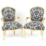Pair of French style cream painted elbow chairs, each having cream and black floral upholstery, each