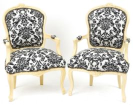 Pair of French style cream painted elbow chairs, each having cream and black floral upholstery, each