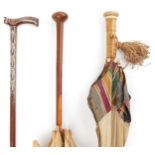 Two early 20th century parasols and a Middle Eastern hardwood walking stick with foliate metal