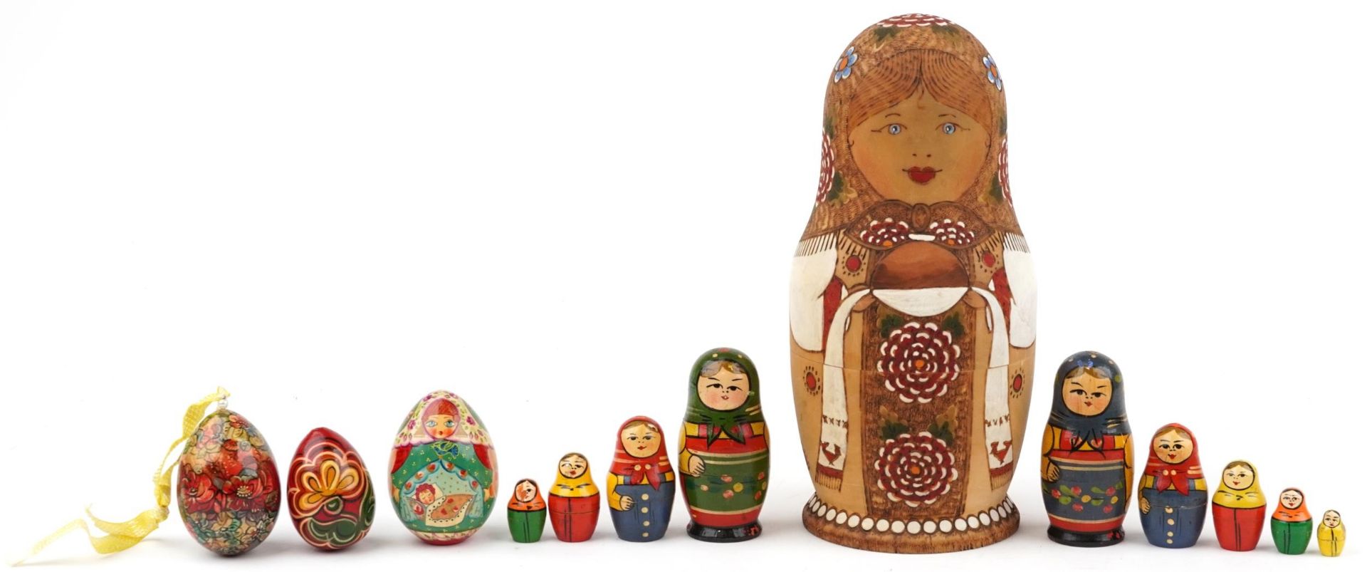 Three Russian Matryoshka stacking dolls and three lacquered eggs, the largest stacking doll hand