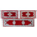 Three Chinese red ground floral rugs including a runner, the largest 255cm x 70cm