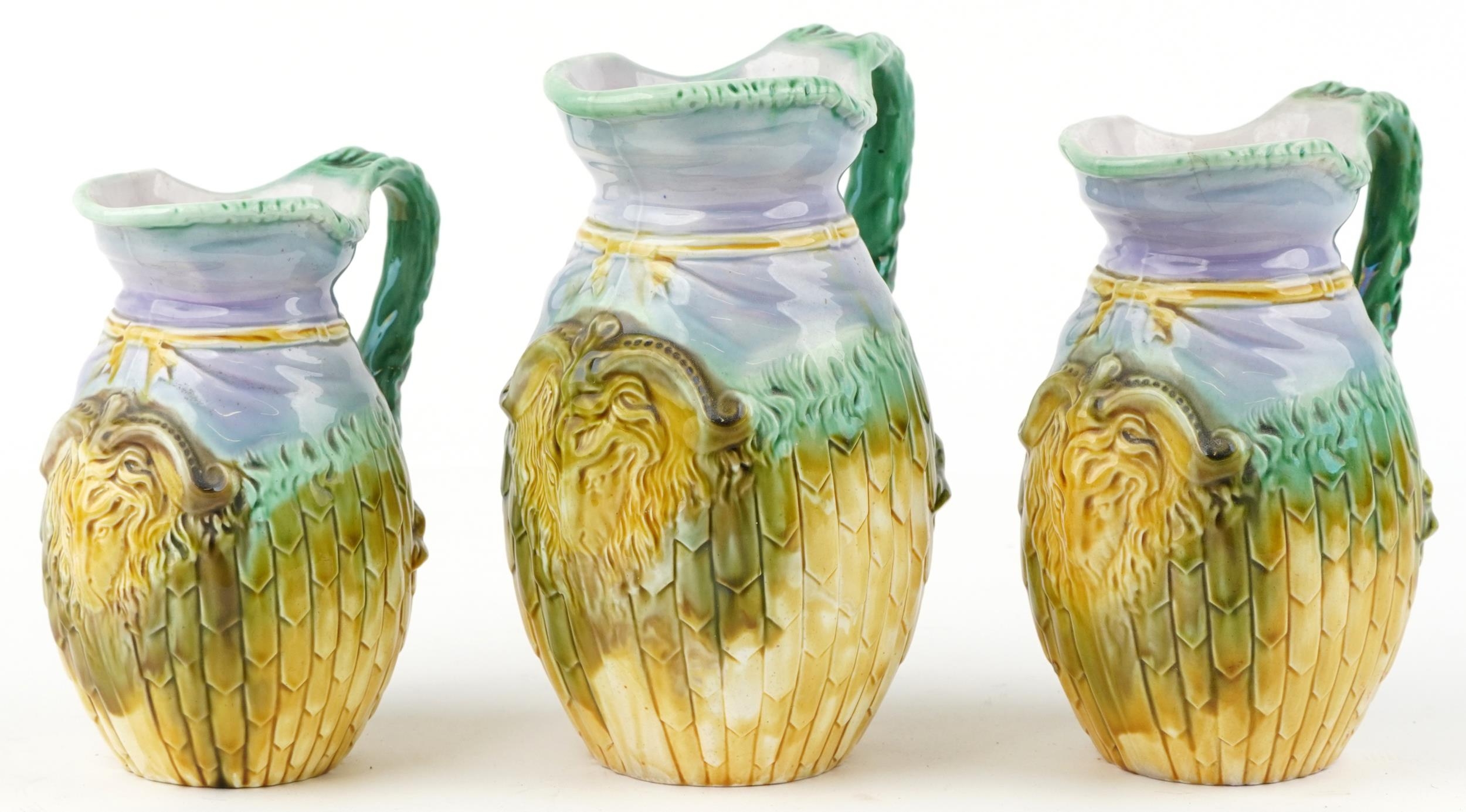 Graduated set of three Majolica jugs, each decorated in relief with a ram's head, the largest 22.5cm