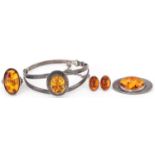 Silver natural amber jewellery comprising hinged bangle, brooch, ring and earrings, the bangle 6.5cm