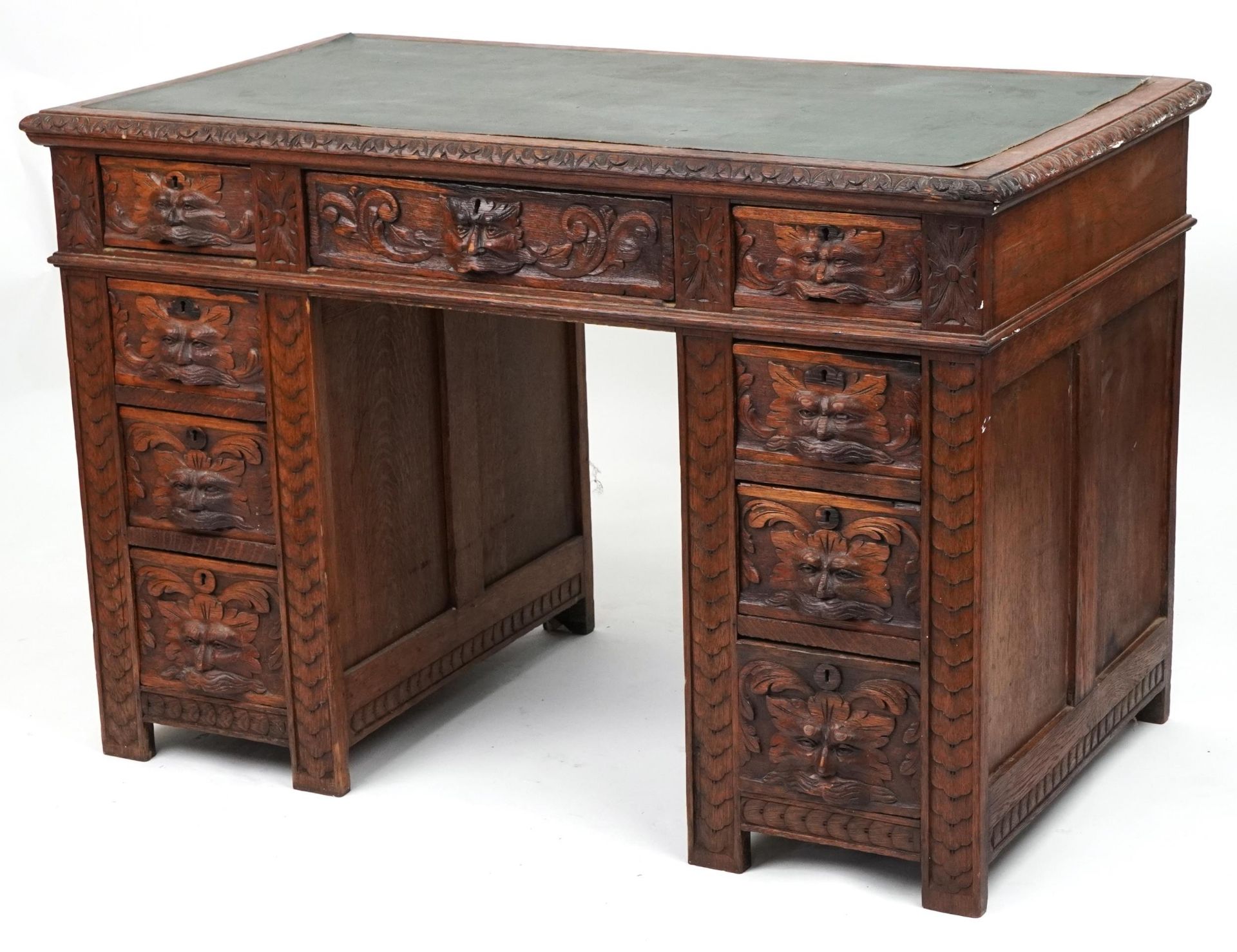 Victorian oak twin pedestal desk carved with a green man masks, fitted with an arrangement of nine