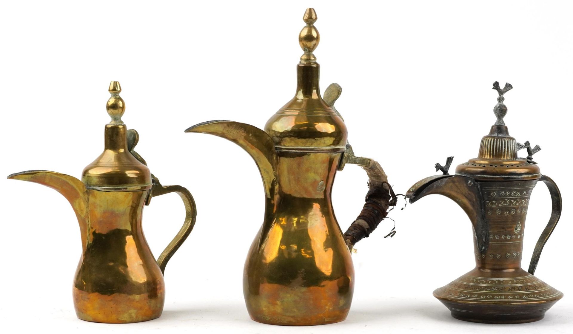 Three Omani brass dallah coffee pots including an example with bird knops, the two others with