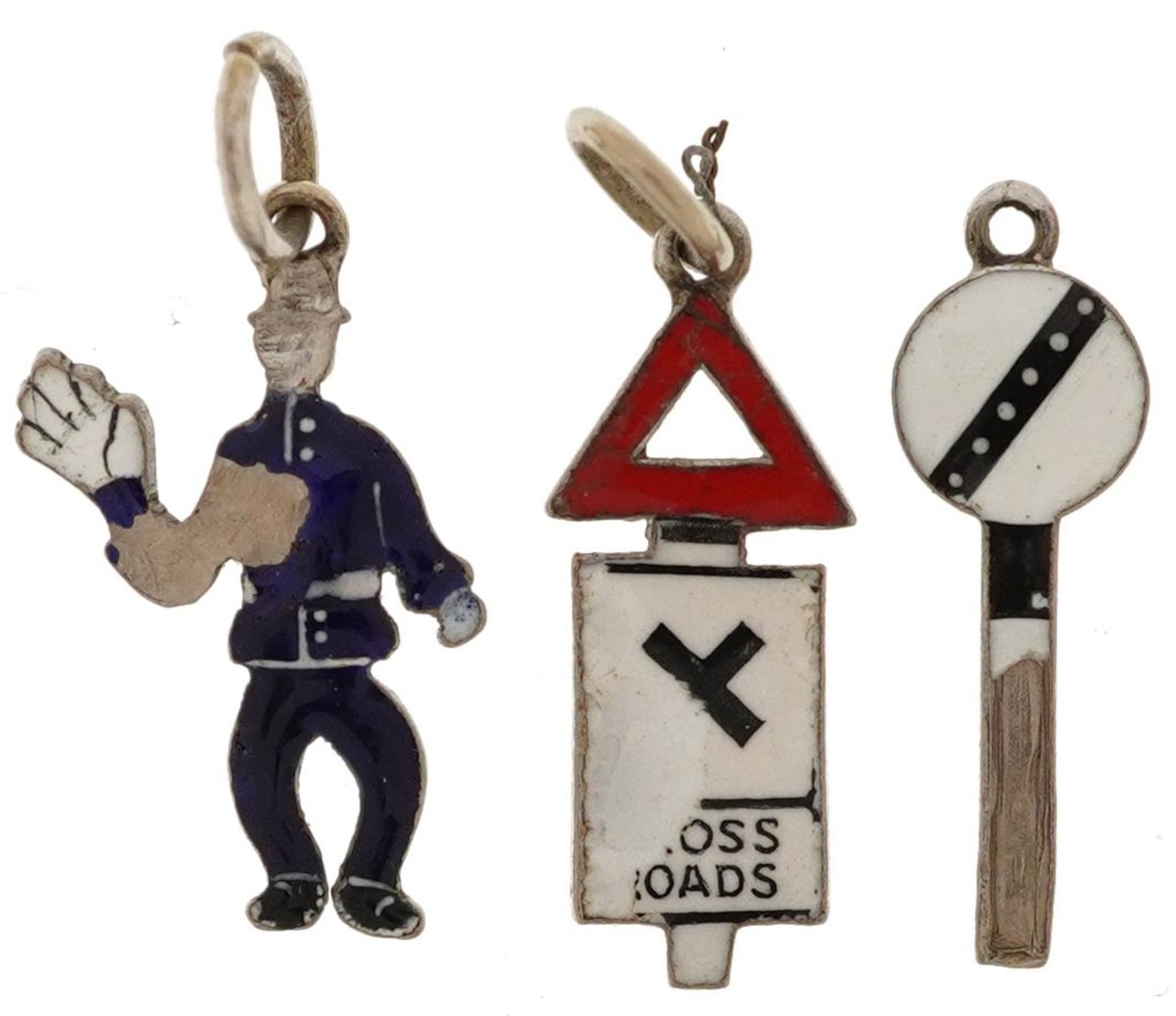 Three 18ct white gold and enamel charms in the form of a policeman, crossroads traffic sign and a