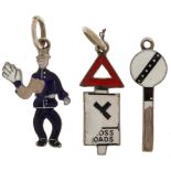 Three 18ct white gold and enamel charms in the form of a policeman, crossroads traffic sign and a