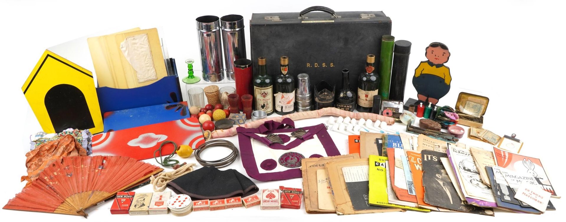 Collection of vintage magician tricks and props including tinplate bottles, playing cards, cups &