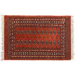 Rectangular Turkish Bokhara peach ground rug having an allover repeat flower head design, 150cm x