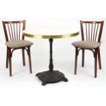 Contemporary circular bistro table with cast iron base and two mahogany chairs with cushions, the