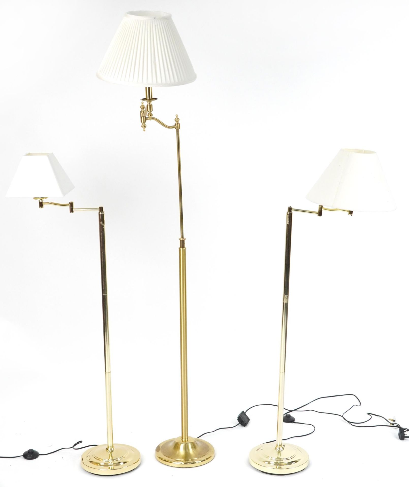 Three contemporary adjustable brass standard lamps with cream shades including a pleated example