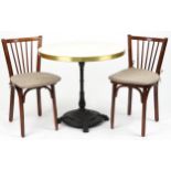 Contemporary circular bistro table with cast iron base and two mahogany chairs with cushions, the