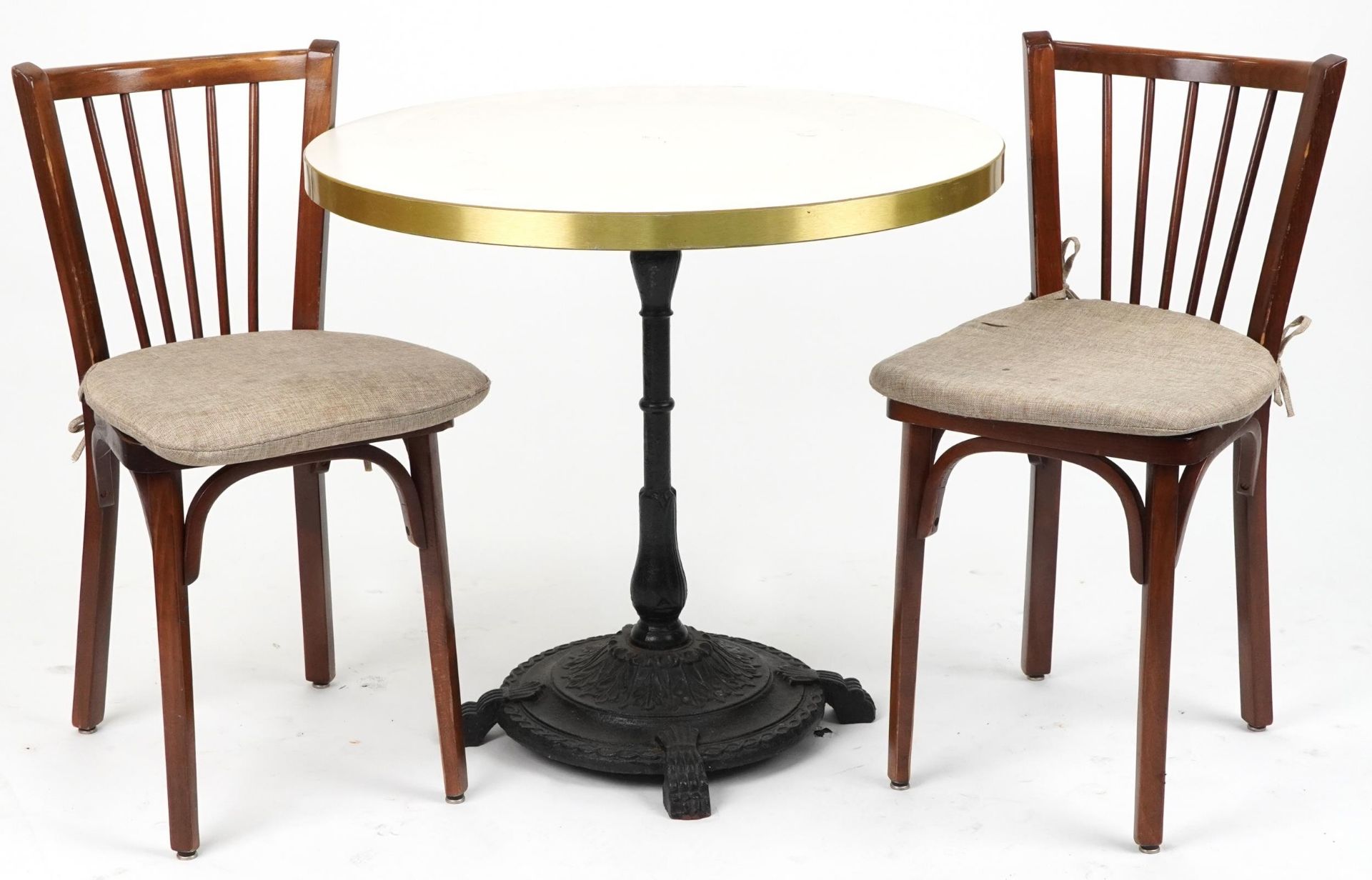 Contemporary circular bistro table with cast iron base and two mahogany chairs with cushions, the
