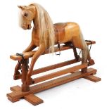 Large carved hardwood rocking horse with leather saddle on hardwood stand having brass plaque