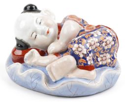 Chinese porcelain figure of a sleeping boy hand painted in the Imari palette, 24cm wide