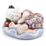 Chinese porcelain figure of a sleeping boy hand painted in the Imari palette, 24cm wide